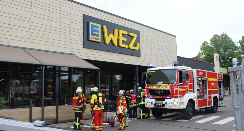 Derzeit läuft ein Großeinsatz der Feuerwehr am Wez Markt an der Ringstraße. Nach ersten Informationen sind zwei Paletten im Leergutraum in Brand geraten. Die Flammen griffen auch auf einen Leergutautomaten über. Durch den Brand breitete sich starker Rauch im gesamten Markt aus.