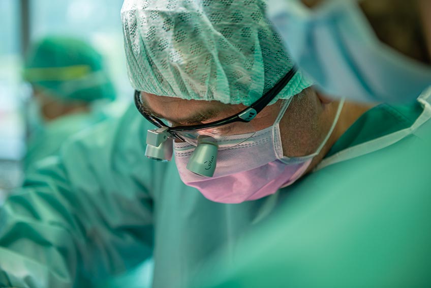 CAD/CAM-gefertigten Sägeschablonen wird zudem die Operationszeit verkürzt und die Passgenauigkeit erhöht. Die Operationsmethode ist allerdings nicht für jeden Patienten geeignet. Die körperliche Konstitution für eine achtstündige Operation muss ebenso vorhanden sein wie eine entsprechende Blutversorgung des Beins. „Wenn die Gefäße im Bein nicht ausreichend stark sind, riskieren wir eine unzureichende Durchblutung des Fußes. All das muss im Vorfeld mittels einer CT-Angiografie untersucht und abgeklärt werden“, sagt Scheer. Grundsätzlich kann jeder gesunde Mensch auch ohne Teile des Wadenbeins gut leben. Das eigentliche Gewicht liegt auf dem parallel verlaufenden Schienbein. „Das Wadenbein verleiht uns etwas mehr Stabilität.“ Dass der Patient aus Hameln mit einer Krücke zur Nachuntersuchung kommt, lässt Dr. Scheer dann aber doch aufhorchen. Doch der Patient beruhigt: „Ich habe mir das Knie verdreht – auf der anderen Seite. Dem Wadenbein geht es gut – dem verbliebenen Teil im Bein und dem im Kiefer.“