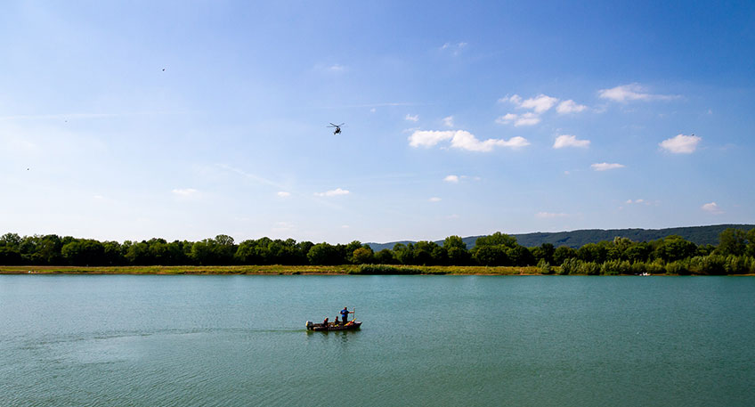 Die Freiwillige Feuerwehr Porta Westfalica wurde am Sonntag, 24.7.2022, gegen 15:14 Uhr zu einem Ertrinkungsunfall auf einem Baggersee am Maschweg alarmiert. Zeugen hatten 2 Personen auf dem See bemerkt, welche um Hilfe riefen und kurz darauf nicht mehr zu sehen waren. Die Feuerwehr suchte mit einem Gro&szlig;aufgebot bis in die Abendstunden - leider blieb die Suche erfolglos.  Bei dem Baggersee handelt es sich um einen aktiven Betrieb am Maschweg, in direkter N&auml;he zum Gro&szlig;en Weserbogen. Es handelt sich um ein Betriebsgel&auml;nde, Betreten und Baden ist nicht erlaubt. Zeugen hatten 2 Personen auf dem See bemerkt, welche  mit Luftmatratzen/kleinem Gummiboot auf dem See waren. Es wurde um Hilfe gerufen, die Personen waren kurz darauf nicht mehr zu sehen. Die Zeugen alarmierten umgehend die Rettungskr&auml;fte.  Die Feuerwehr Porta Westfalica setzte 2 Boote auf dem See zur Suche ein. Auf dem Wasser oder an den Halteseilen der Schwimmbagger konnten keine Personen aufgefunden werden. Parallel wurden alarmiert: Die Tauchergruppen der Feuerwehren Petershagen, Lemgo und Hameln; die DLRG Ortsgruppe Vlotho und ein Polizeihubschrauber. Die DLRG setzte eine Drohne mit W&auml;rmebildkamera zur Suche ein, der Polizeihubschrauber Hummel suchte den See ebenfalls ab.  An einer Bucht wurden pers&ouml;nlichen Gegenst&auml;nde und Kleidung gefunden, danach handelte es sich um eine m&auml;nnliche und eine weibliche Person. Die Badehilfen wurden ebenfalls in Ufern&auml;he aufgefunden.   Durch die Tauchergruppen wurden 2 weitere Boote eingesetzt, au&szlig;erdem wurde der See mit Sonarger&auml;ten abgesucht. Taucher suchten vom Ufer und von den Booten aus im See nach den Vermissten. Der Baggersee ist bis zu 30m tief und f&auml;llt kurz nach dem Ufer steil ab. Die Taucher berichteten von schlechten Sichtbedingungen unter Wasser, sogenannter Nullsicht. Durch das Sonar wurden Echos unter Wasser ausgemacht, diese wurden durch die Taucher &uuml;berpr&uuml;ft. Die Vermissten wurden dabei nicht aufgefunden.  Die Suche wurde gegen 20:50 Uhr eingestellt und alle Ma&szlig;nahmen zur&uuml;ckgenommen. Neben den o.g. Kr&auml;fte war auch das DRK Barkhausen ls Abl&ouml;sung des Rettungsdienstes sowie Notfallseelsorger zur Betreuung der Angeh&ouml;rigen vor Ort.